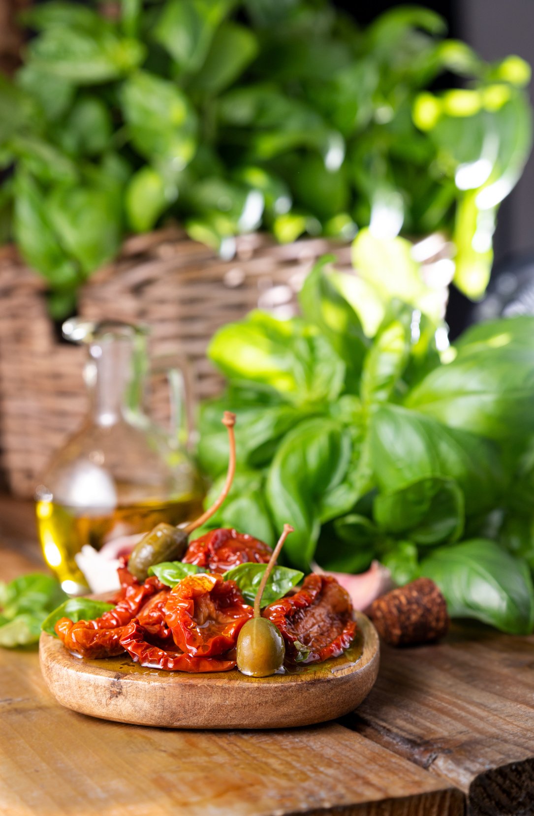 Dried tomatoes in olive oil and capers in piala, basil next to the product. Leaking oil. Traditional Italian and Spanish appetizer for aperitivo and toast.